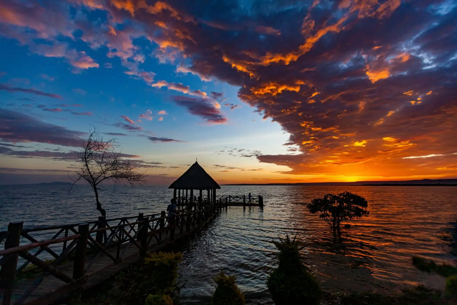 Wooden jetty and thatched gazebo on Lake Victoria at sunset